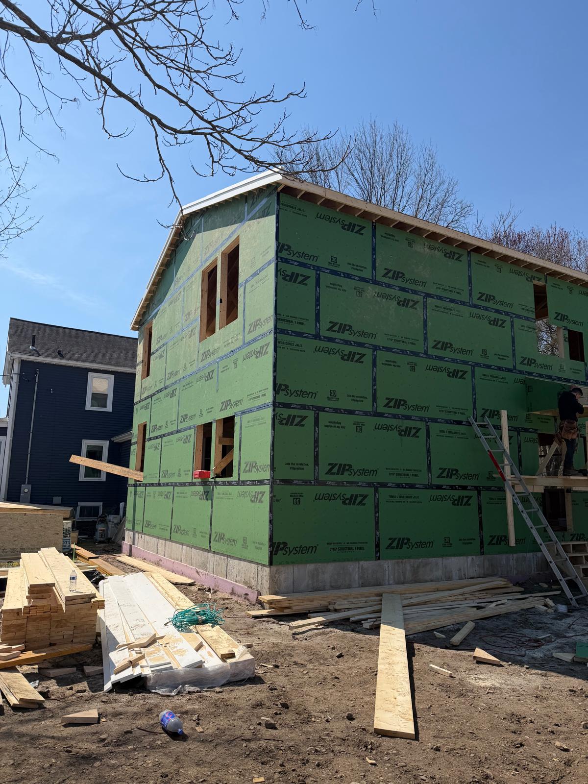 Framed addition with green exterior sheathing and window openings