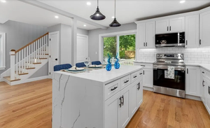 Remodeled kitchen with white cabinets, an island, and pendant lighting