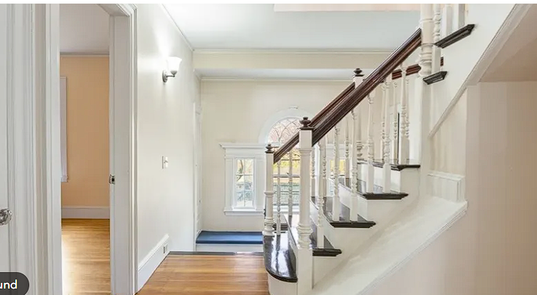 Historic interior staircase with white balusters, dark wood handrail, and hardwood floors in a Salem, MA home