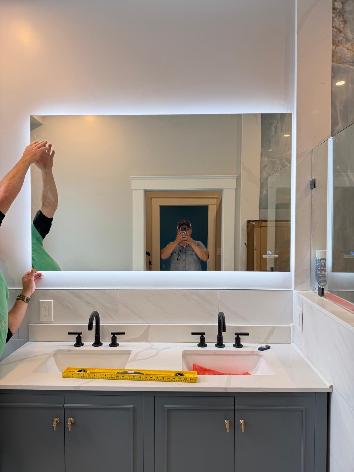 Double bathroom vanity with blue-gray cabinets and a wide illuminated mirror